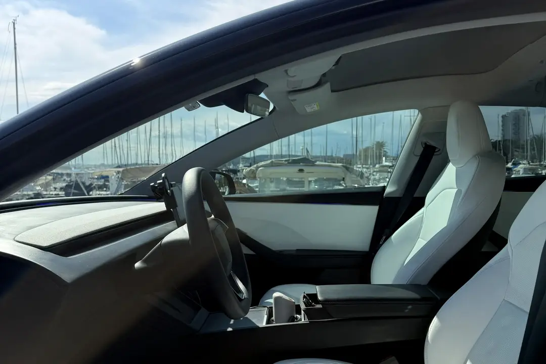Intérieur avant de la Tesla Model 3 ELYSIA, sièges en cuir blanc et port visible par le pare-brise