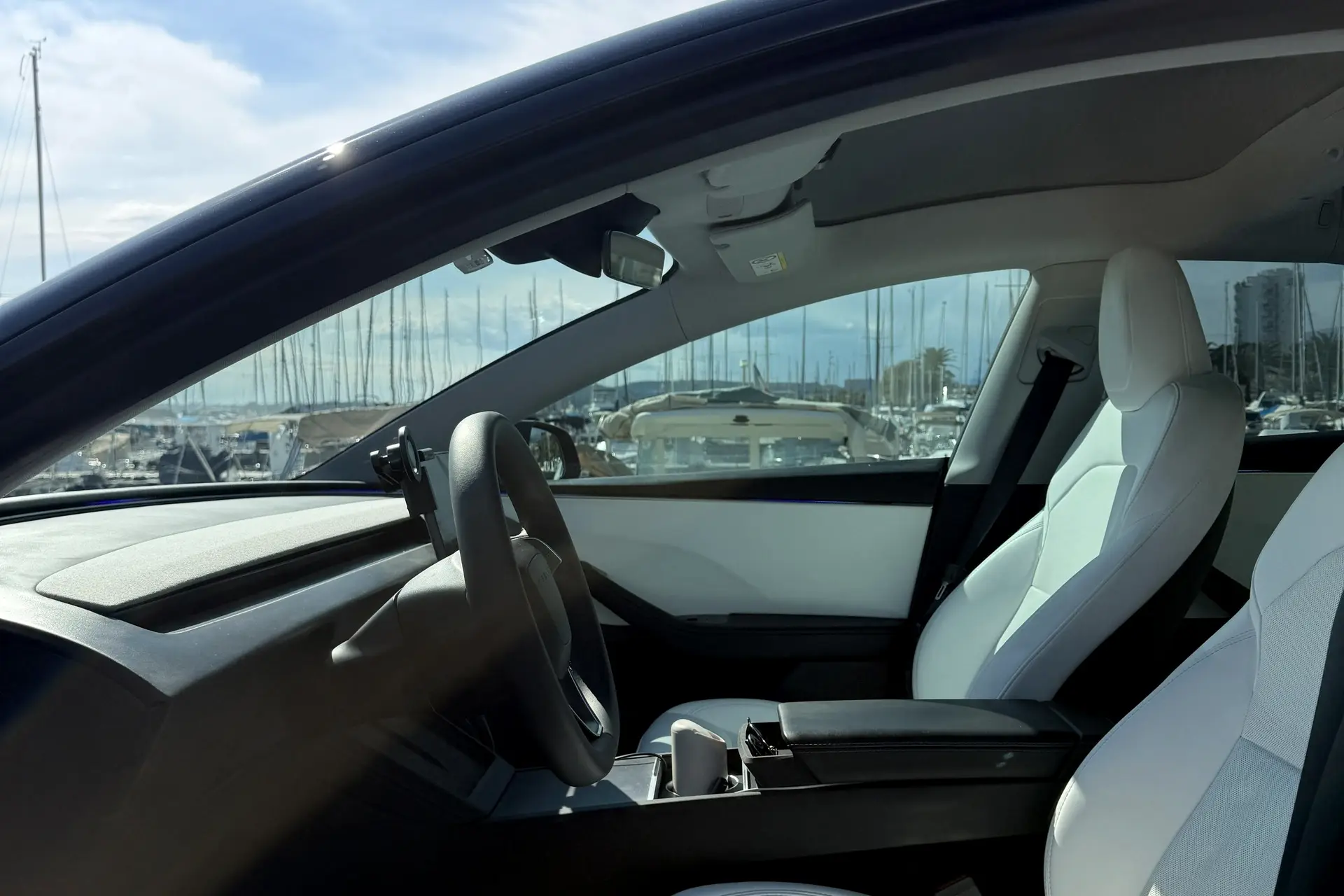 Intérieur avant de la Tesla Model 3 ELYSIA, sièges en cuir blanc et port visible par le pare-brise